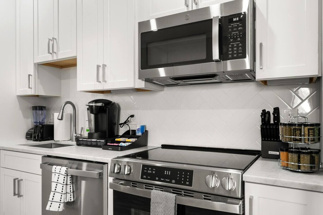 Une cuisine moderne équipée d’appareils électroménagers en acier inoxydable, notamment un four à micro-ondes, une machine à café et un four.