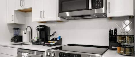 Une cuisine moderne équipée d’appareils électroménagers en acier inoxydable, notamment un four à micro-ondes, une machine à café et un four.