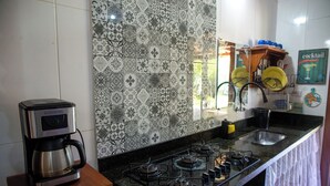 A kitchen with a gas stove, a coffee maker, and a patterned backsplash. - Casa com Piscina e Churrasqueira no Pantanal (Angra dos Reis)