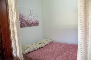 A bedroom with a bed, a floral-patterned pillow, and a wall painting of two people embracing. - Casa com Piscina e Churrasqueira no Pantanal (Angra dos Reis)