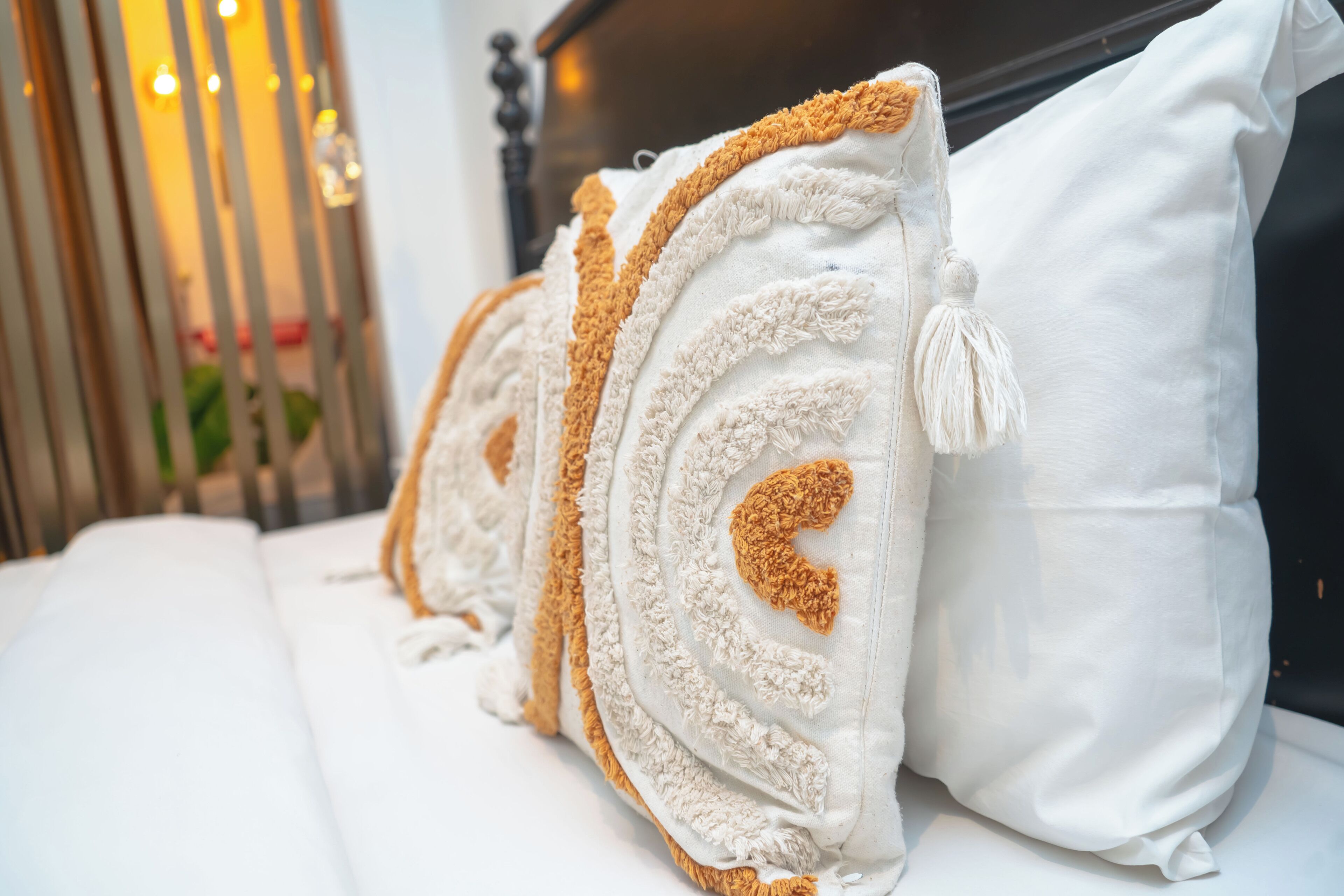 A bed with white bedding and decorative pillows with tassels.