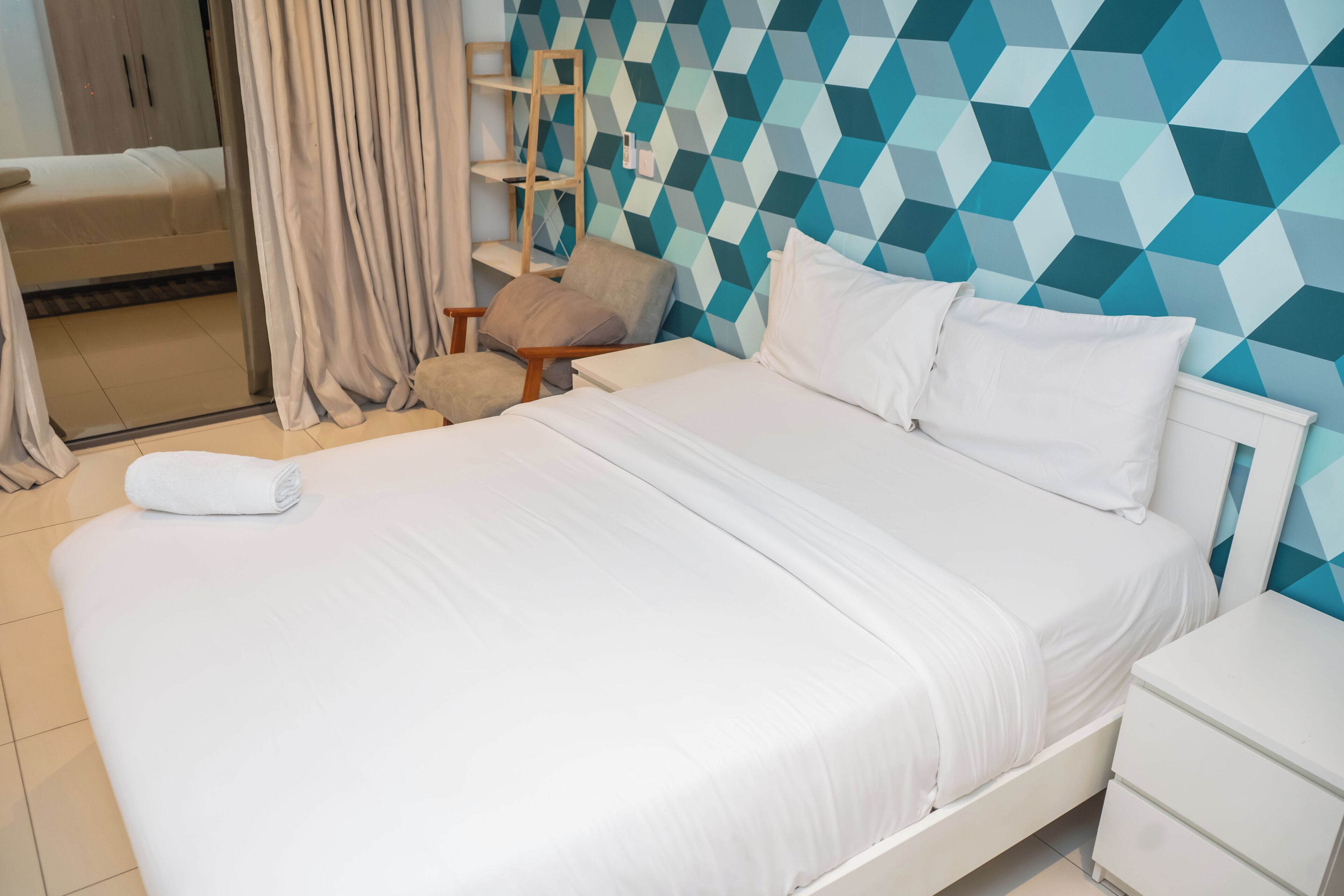 Une chambre d’hôtel comprenant un lit, une table de chevet, une chaise et une armoire.