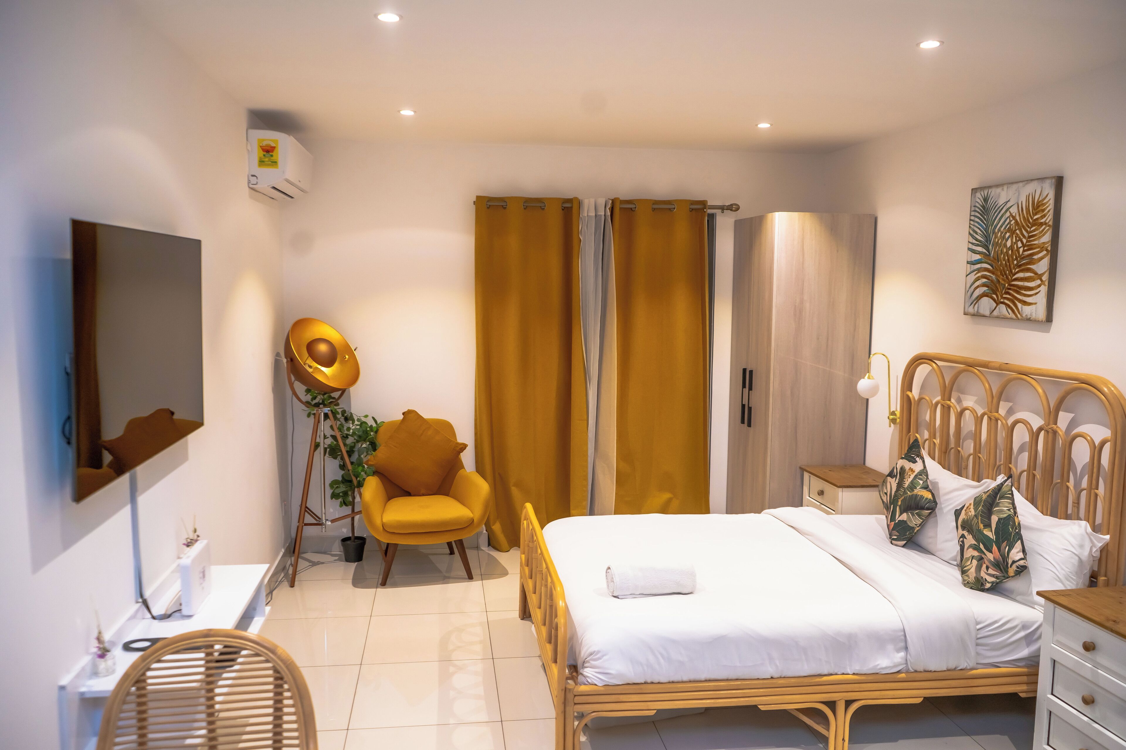 Une chambre d’hôtel comprenant un lit, une chaise, une table de chevet, un miroir et un téléviseur fixé au mur.