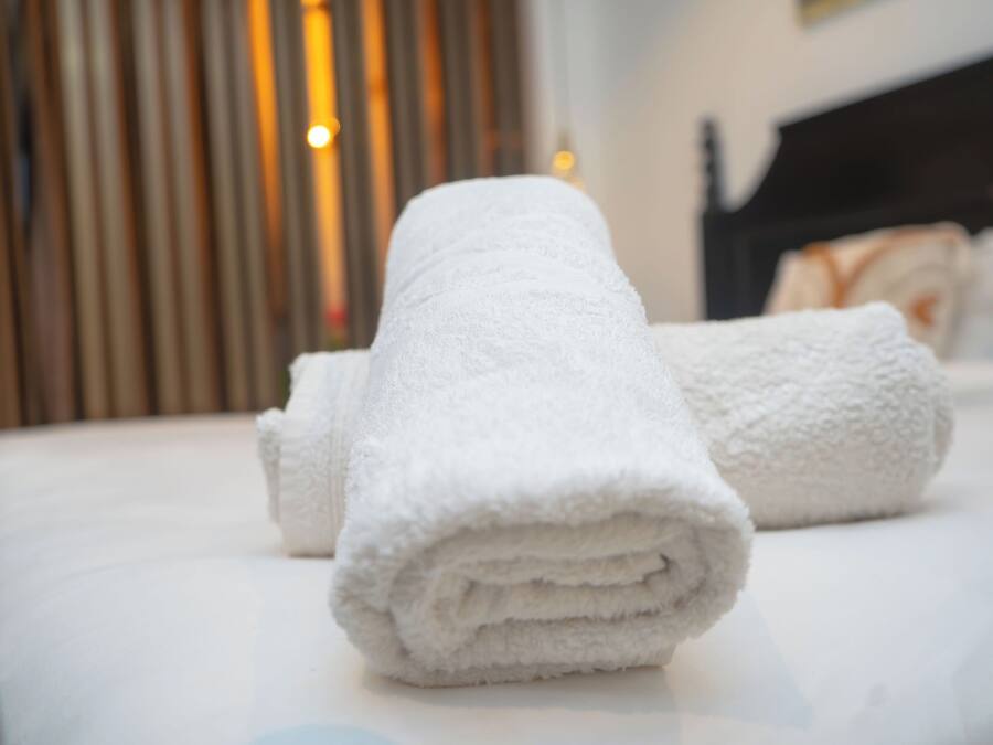 Een keurig opgevouwen witte handdoek op een bed in een hotelkamer.