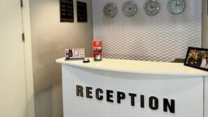 Un mostrador de recepción con un cartel que dice "RECEPTION" y tres relojes encima.
