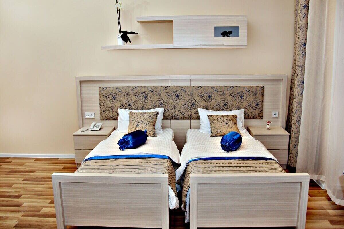 A double room with two beds, a wooden headboard, bedside tables, and a small shelf above the beds.