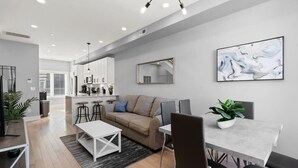 A modern living room with a sofa, coffee table, and dining area with chairs and a table.