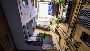 A narrow, multi-level courtyard with balconies, railings, and potted plants. - Vico Santa Luciella 20 (Naples)