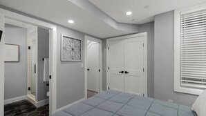 Une chambre à coucher avec un lit, une armoire, une porte et une fenêtre avec des stores.