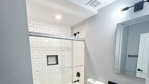Une salle de bain moderne avec une baignoire blanche, des toilettes et un meuble-lavabo doté d’un plan de travail noir.