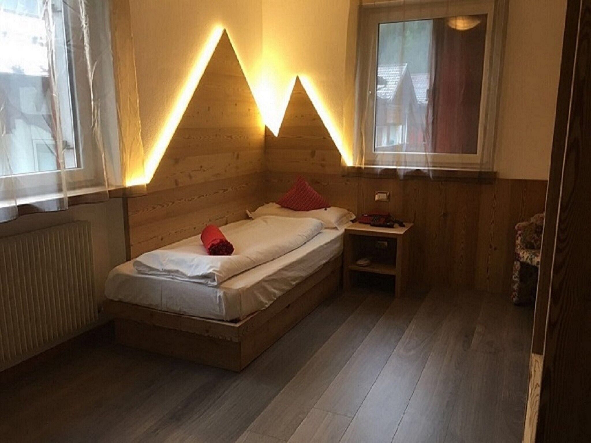 Ein Einzelbett in einem Zimmer mit Holzwänden und einem Fenster.
