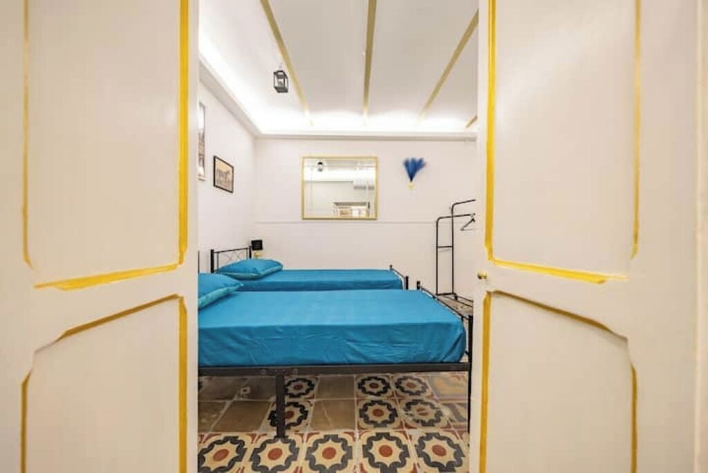 A room with two beds, a mirror, and a patterned floor.