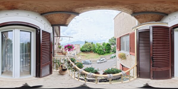 A balcony with a view of a street and mountains.