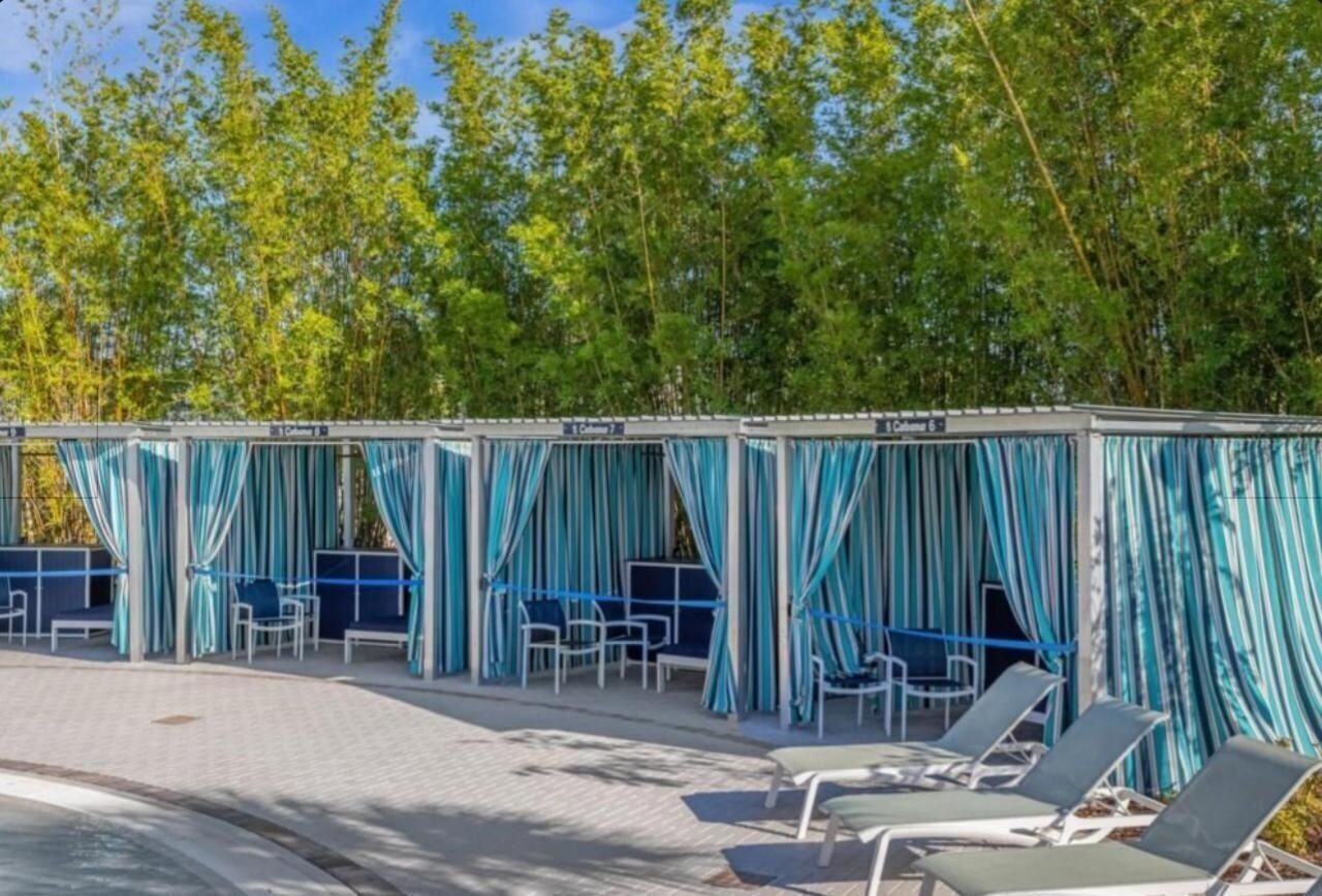 A covered outdoor seating area with blue curtains and lounge chairs.