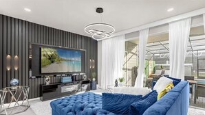 Un salon moderne avec un grand téléviseur à écran plat, un canapé bleu et une table basse en verre.