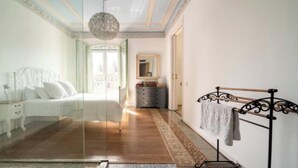 Ein Schlafzimmer mit Bett, Nachttisch, Kommode, Spiegel und einer Pendelleuchte.