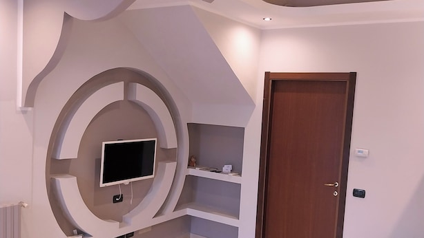 A bedroom with a TV mounted on the wall, a door, and a bed. - B&B linate (Peschiera Borromeo)