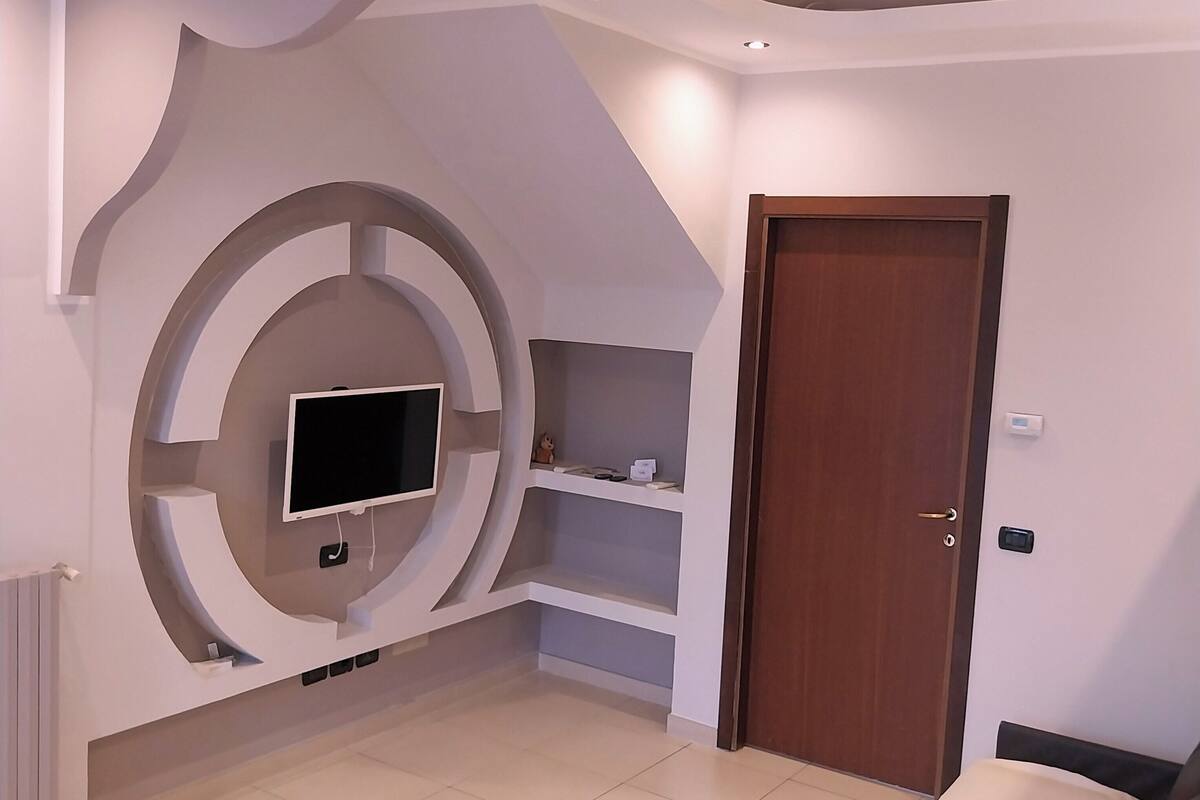 A bedroom with a TV mounted on the wall, a door, and a bed.