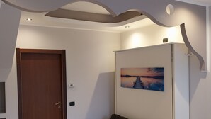 A modern room with a wooden door, a sofa, a chair, and a wall-mounted painting. - B&B linate (Peschiera Borromeo)
