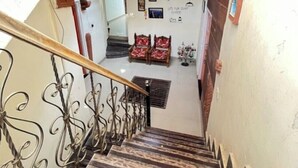 Un escalier avec une rampe en métal, des marches en marbre et un mur décoré de tableaux encadrés et d’objets suspendus.