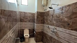 Une salle de bain avec des murs en marbre, des toilettes, une douche et une fenêtre.