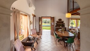 A dining area with a wooden table, chairs, and a view of a green landscape through an open door. - Countryside finca in Mallorca with Private Pool, Tradition and Nature (Illes Balears)