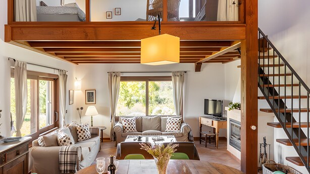 A spacious living area with a wooden dining table, green chairs, a sofa, and a staircase. - Countryside finca in Mallorca with Private Pool, Tradition and Nature (Illes Balears)
