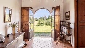 An open doorway leading to a garden, wooden furniture, and a bookshelf. - Countryside finca in Mallorca with Private Pool, Tradition and Nature (Illes Balears)