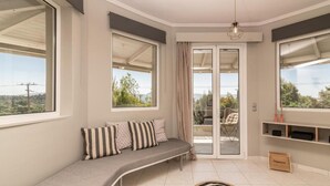 A modern living room with a curved sofa, large windows, and a view of the outdoors.