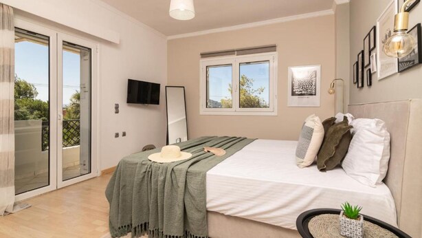 A bedroom with a bed, a TV, a window, and a balcony.