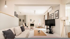 A modern living room with a sofa, a coffee table, a TV, and a fireplace.
