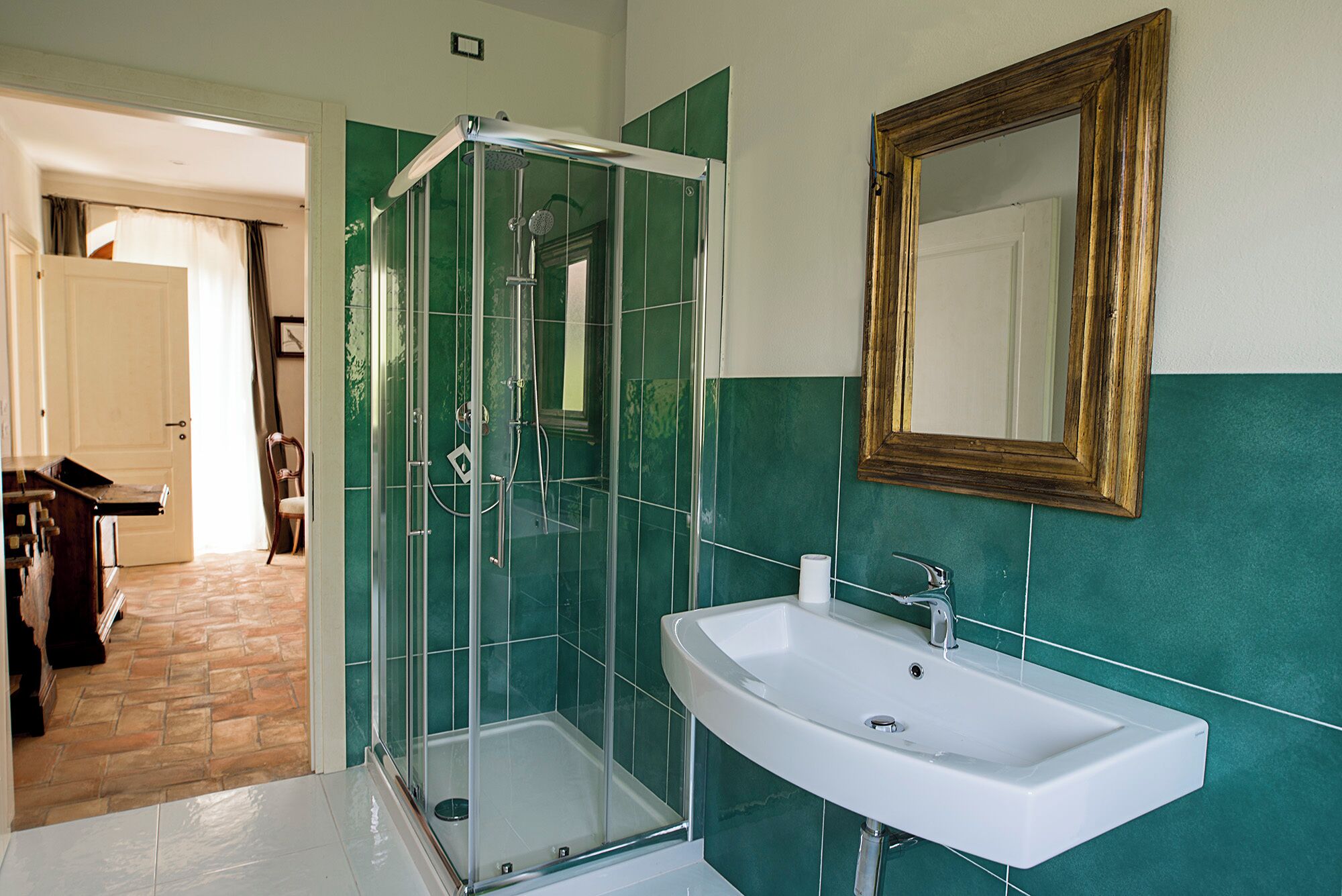 Une salle de bain avec une douche à parois de verre, un lavabo blanc et un miroir avec un cadre en bois.