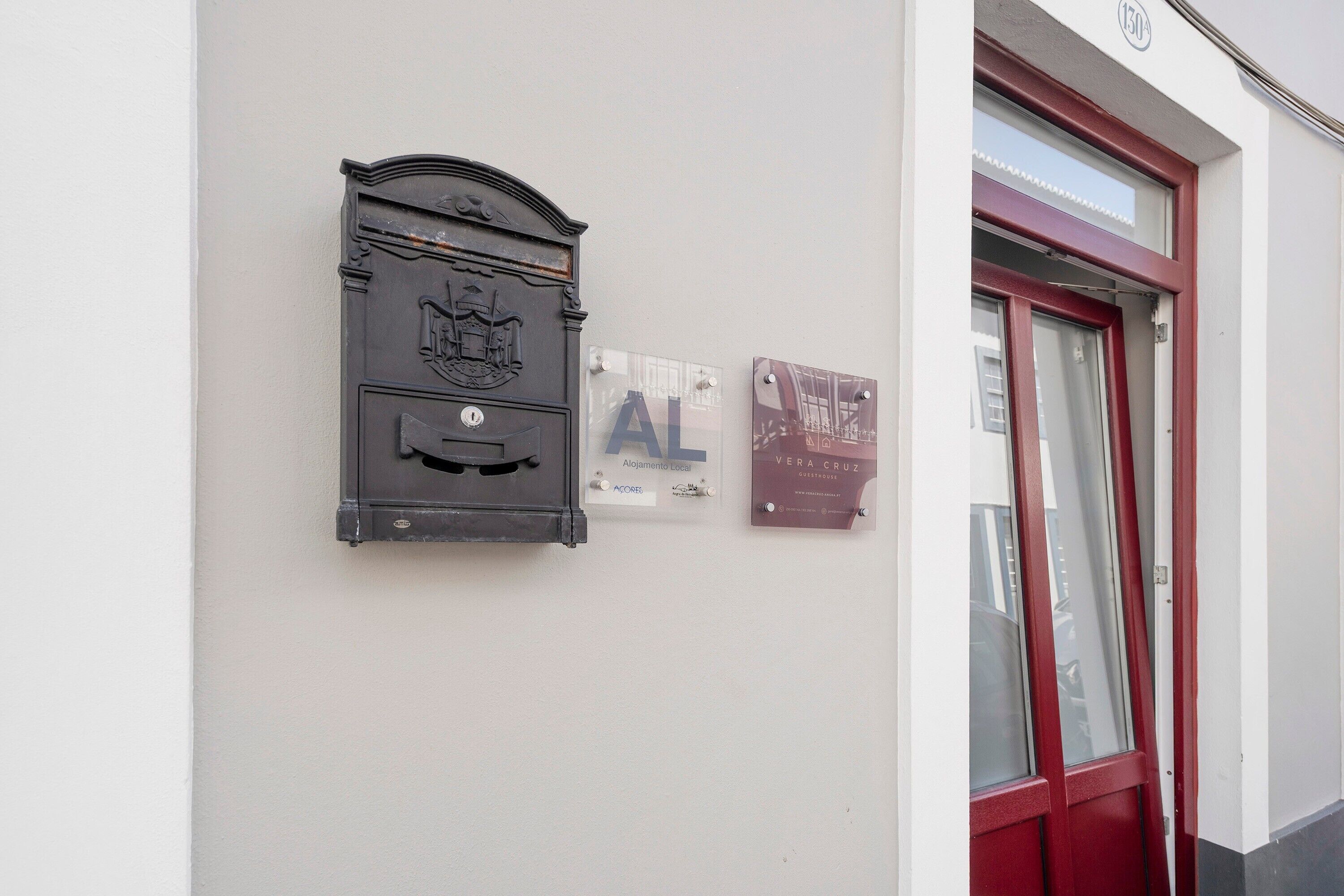 A mailbox, a plaque with the letter 'A', and a door with a red frame.