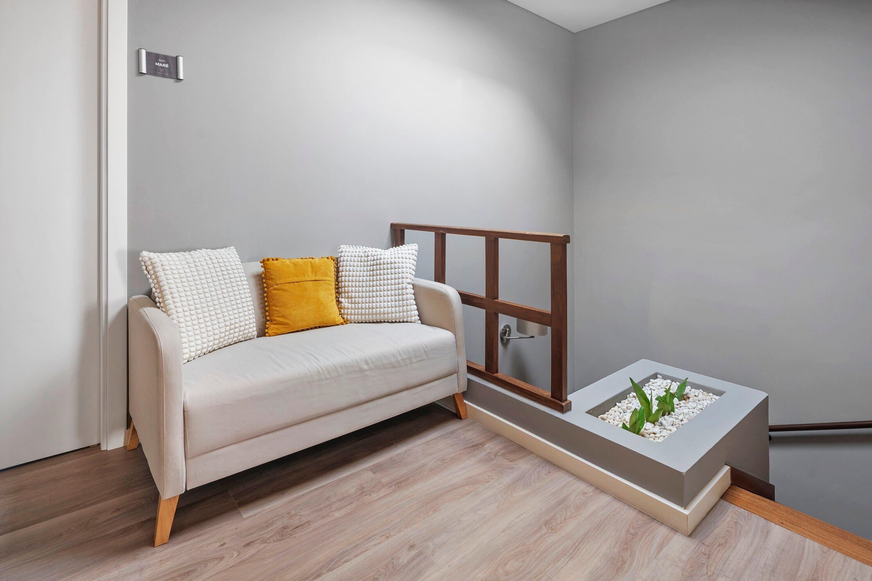 Una habitación minimalista con un sofá, una pequeña mesa de madera y un jardín vertical integrado.