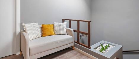 Una habitación minimalista con un sofá, una pequeña mesa de madera y un jardín vertical integrado.
