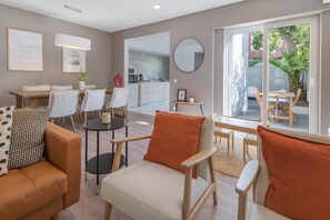 A modern interior with a dining area, a kitchen, and a living space with a sofa and chairs.