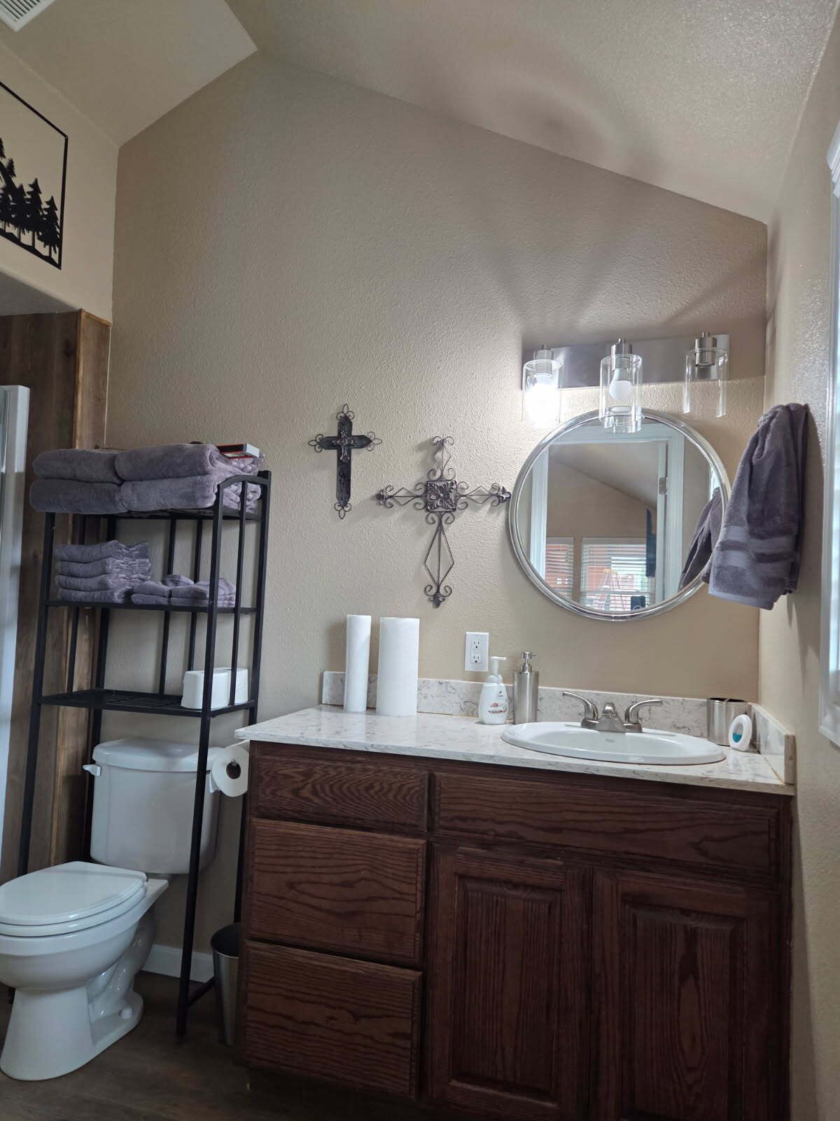 A bathroom with a toilet, a sink, a mirror, and a towel rack.