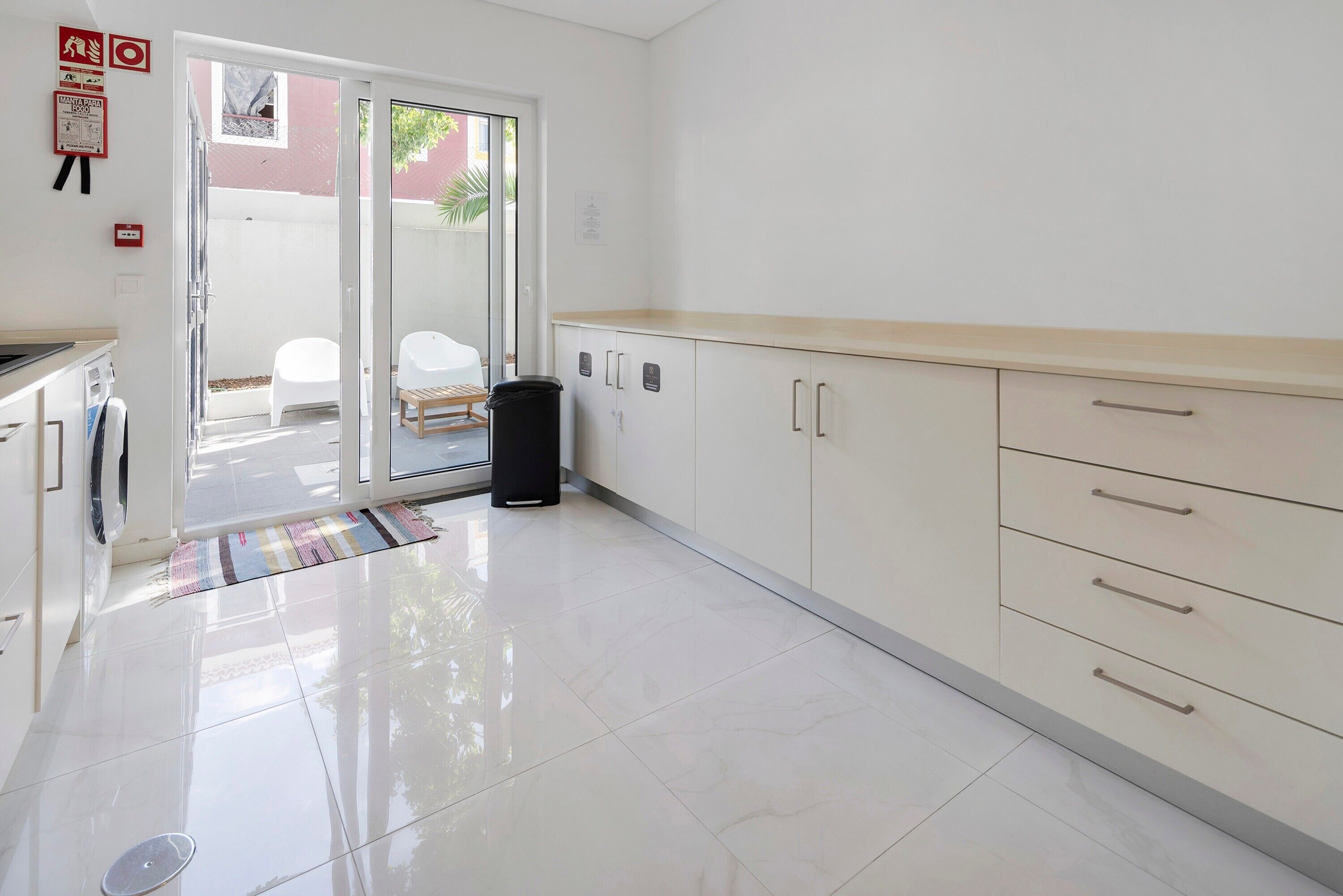 A clean, modern kitchen with white cabinets, a countertop, and a sliding glass door leading to an outdoor area.