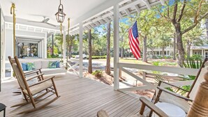 A covered porch with wooden flooring, rocking chairs, and an American flag. - NEW 2 Blocks to Camp WaterColor with LSV, Bikes, and more! (Santa Rosa Beach)