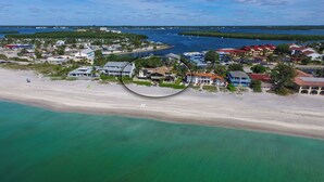 Vista aérea de um resort costeiro com propriedades na orla, um porto de iates e uma praia de areia.