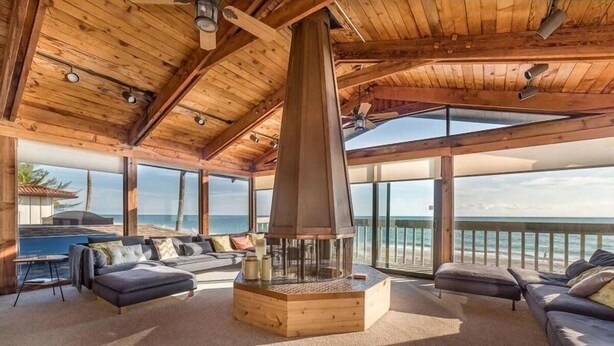 Um quarto espaçoso com uma lareira grande, assentos confortáveis e vista para o oceano.