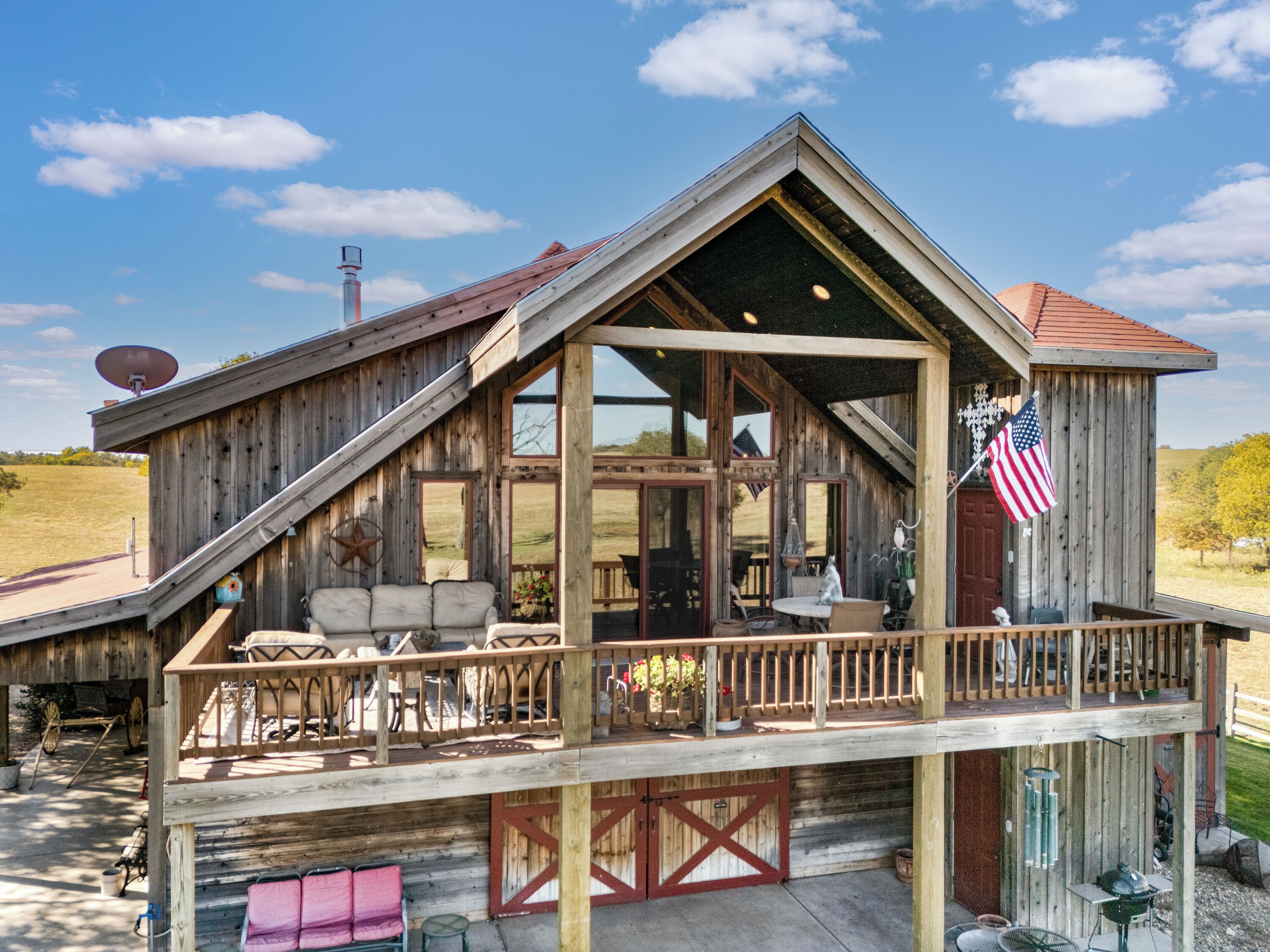 A wooden cabin with a porch, large windows, and an American flag.