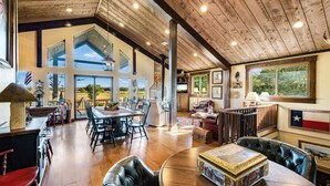 A spacious living area with a high ceiling, wooden beams, and large windows offering views of the outdoors. - The Barn at Quail Creek Ranch - 2 Bedroom Peaceful Ranch Retreat (Wheeler)
