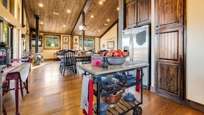 A spacious kitchen with wooden floors, a central island with a bowl of apples, and a large refrigerator. - The Barn at Quail Creek Ranch - 2 Bedroom Peaceful Ranch Retreat (Wheeler)