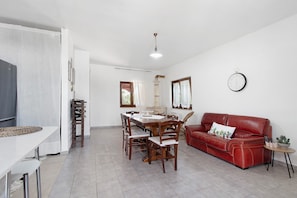 A dining area with a table and chairs, a red sofa, and a clock on the wall. - Villa Mario Pool and Relax: Private Pool & 6,000 m² Garden in Puglia (Mottola)
