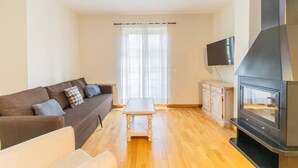 Una sala de estar con sofá, mesa de centro, televisor y chimenea.