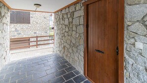 Un pasillo con paredes de piedra, una puerta de madera y piso de baldosas.