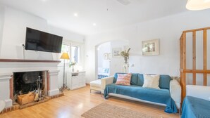 A modern living room with a fireplace, sofa, TV, and wooden beams. - Authentic Mediterranean Villa (Cala Sant Vicenç)