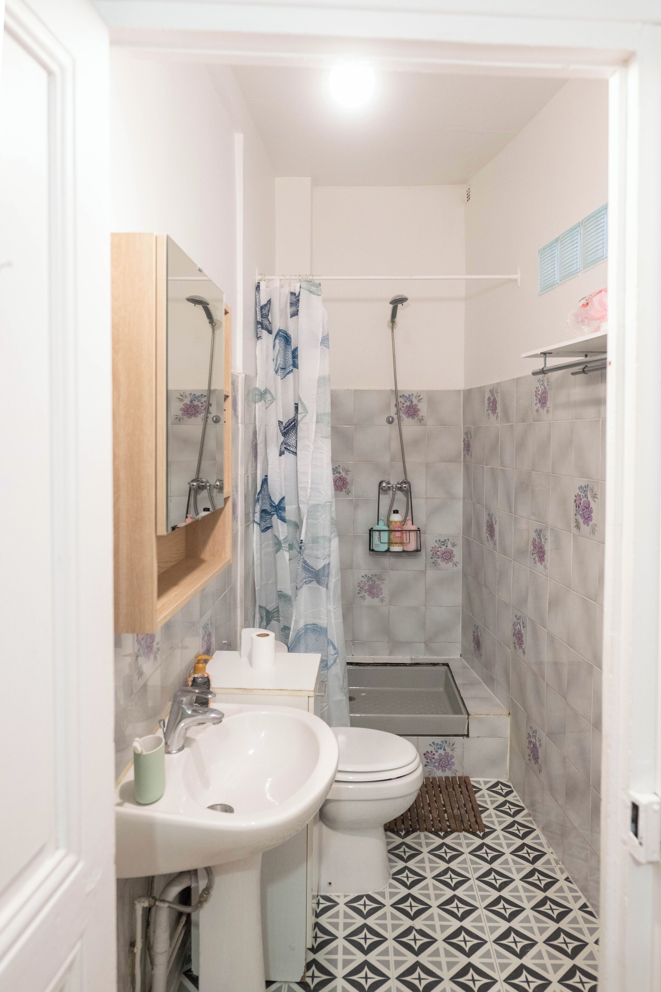 A bathroom with a sink, toilet, shower, and a mirror.