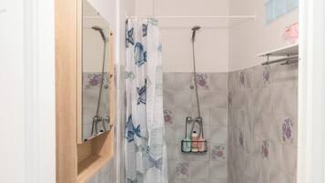 A bathroom with a sink, toilet, shower, and a mirror.